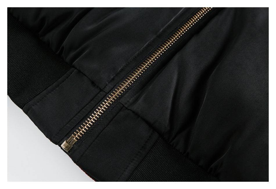 Close-up of the black jacket's brass-tone front zipper and ribbed hem.