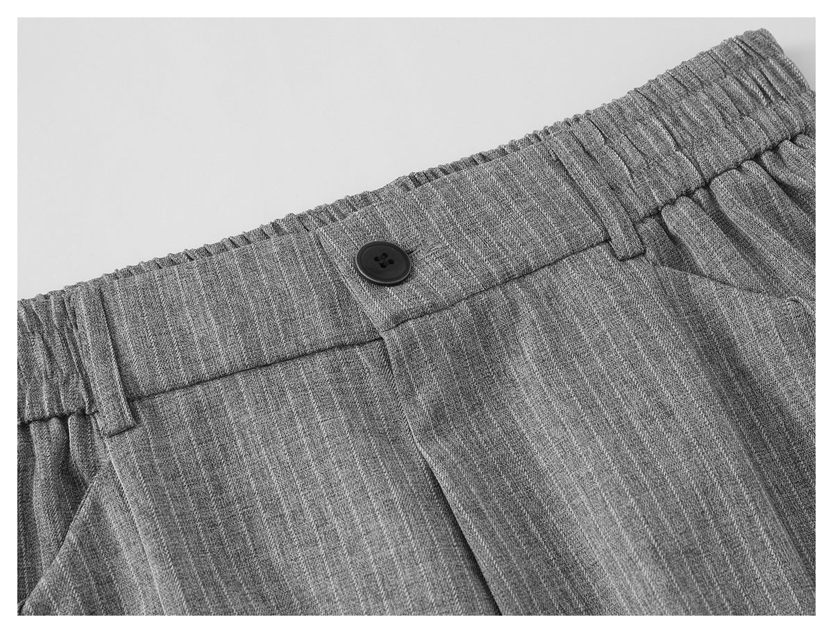 Close-up of the gray pinstriped trousers' elastic waistband, belt loops, and black button.