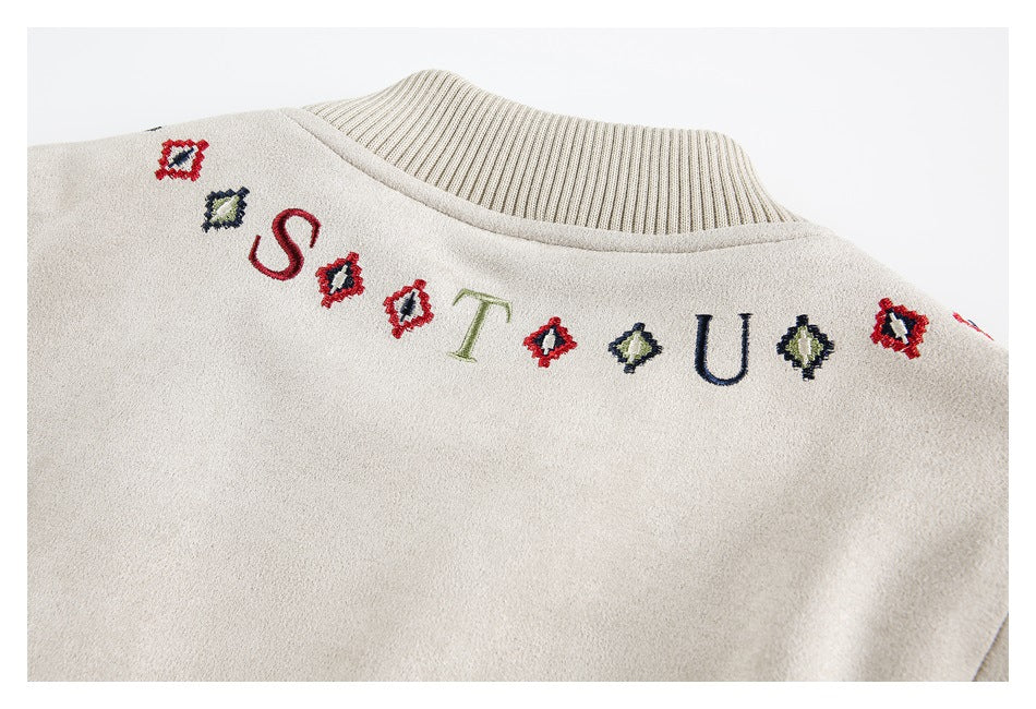 Back collar of a light beige jacket with ribbed trim and embroidered letters and small colorful motifs.