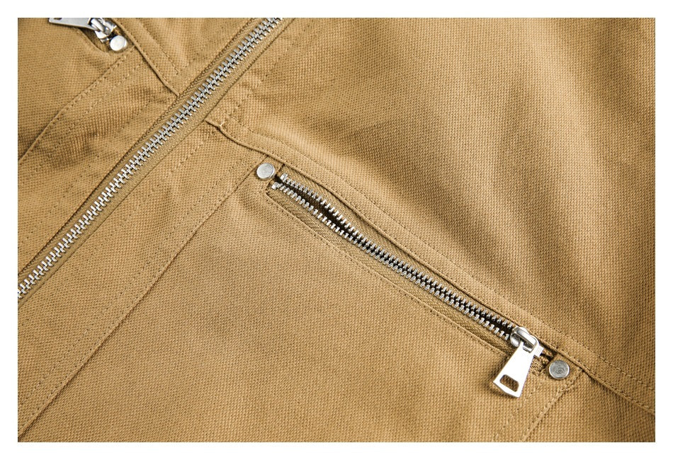 Close-up of a tan jacket's silver zippered pocket, stitching, and textured surface.