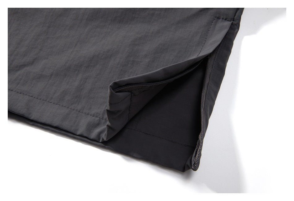 Close-up of dark charcoal pants showing a zippered side opening and stitched panel.
