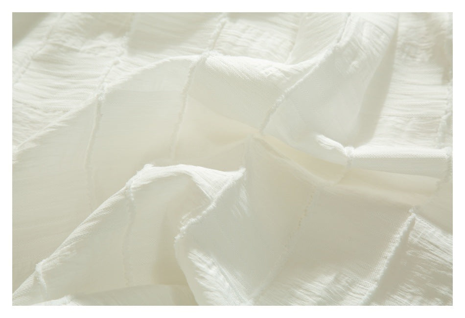 Close-up of folded ivory fabric with textured panels and visible seam details.