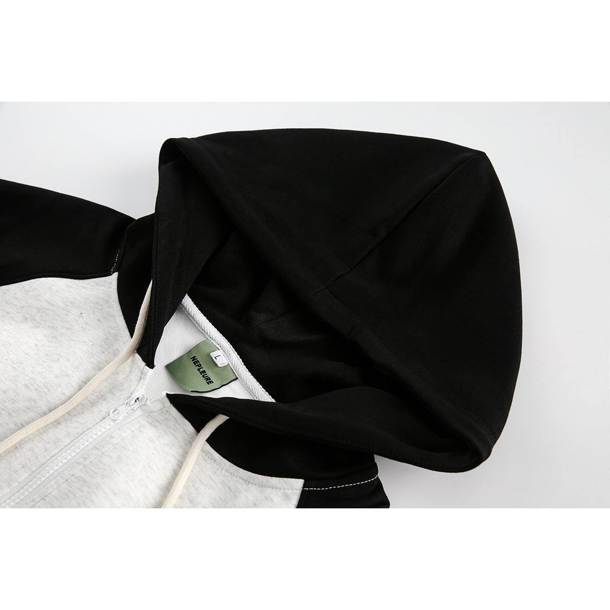 Close-up of the black hood and light gray neckline of a hoodie, with the zipper and neck label visible.