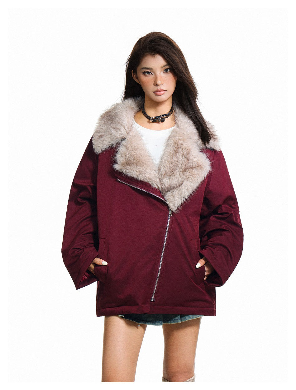 Model wearing a burgundy jacket zipped diagonally, with a wide light plush collar and roomy sleeves.