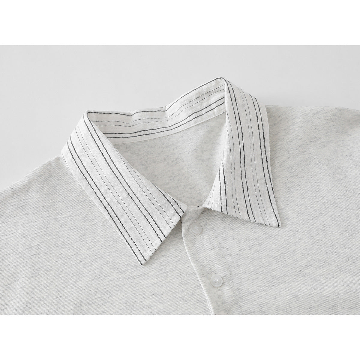 Close-up of a light heather gray polo shirt collar with narrow black pinstripes and white buttons.