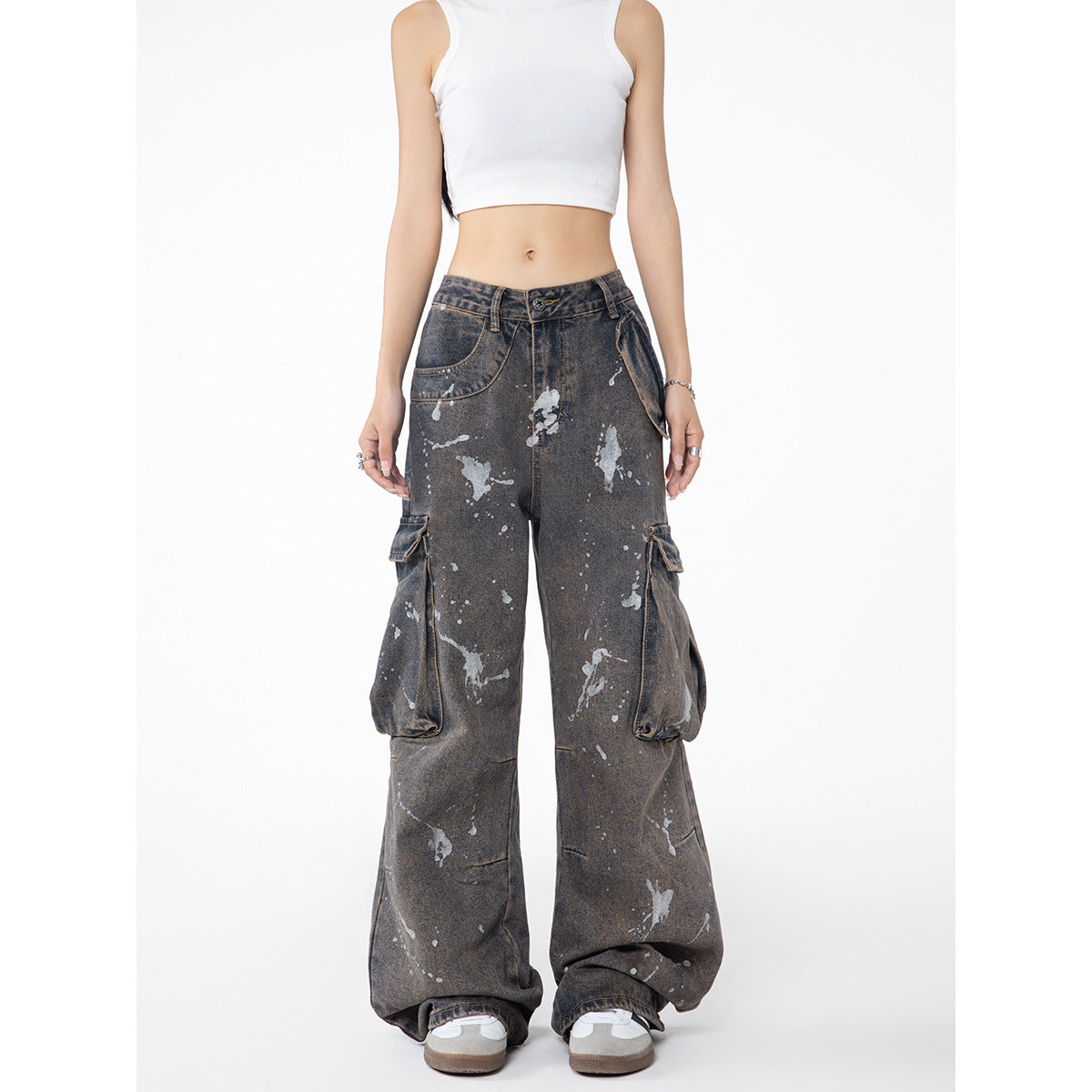 Front view of a model wearing charcoal-gray paint-splatter cargo jeans with oversized side pockets and wide legs.