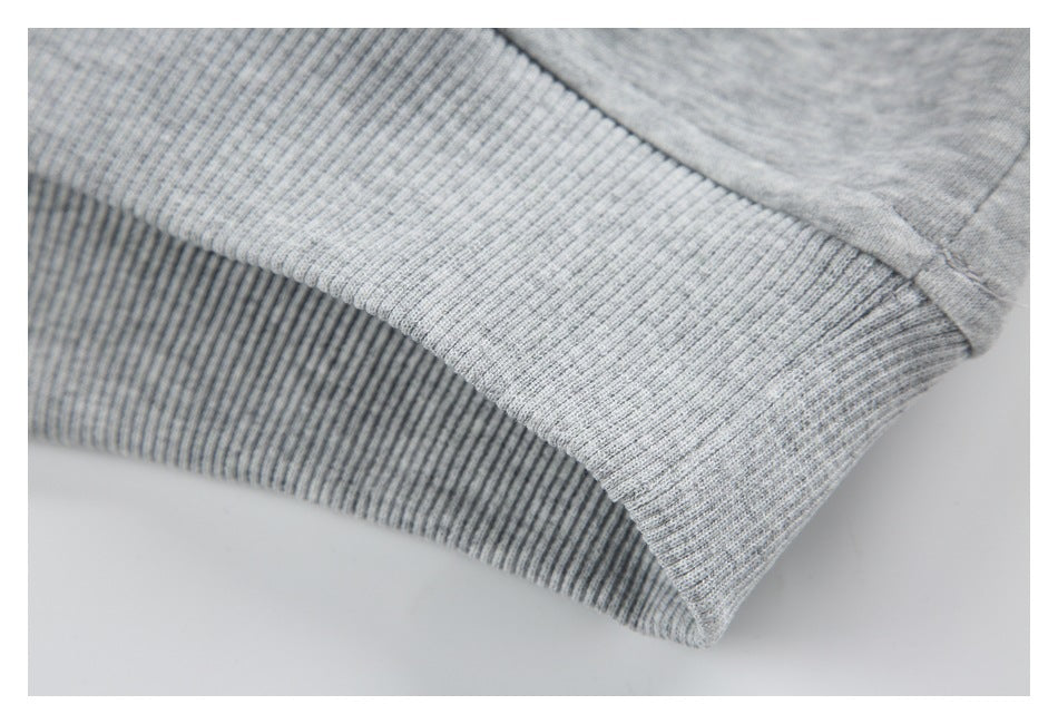 Close-up of the wide ribbed hem and seam on a heather gray sweatshirt.