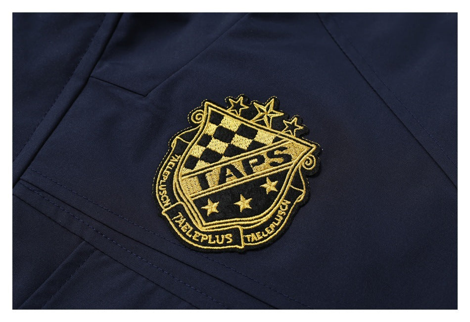 Close-up of a gold-and-black embroidered crest on a dark navy jacket.