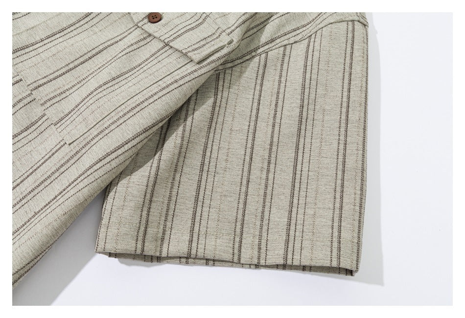 Close-up of a short sleeve and buttoned chest pocket on a beige shirt with thin dark stripes.