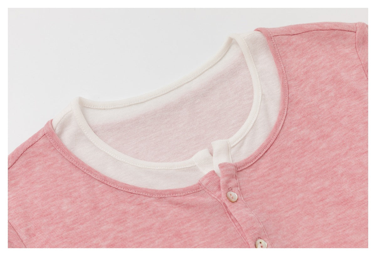 Close-up of a heather-pink top with a white inner neckline and small buttons on the front placket.