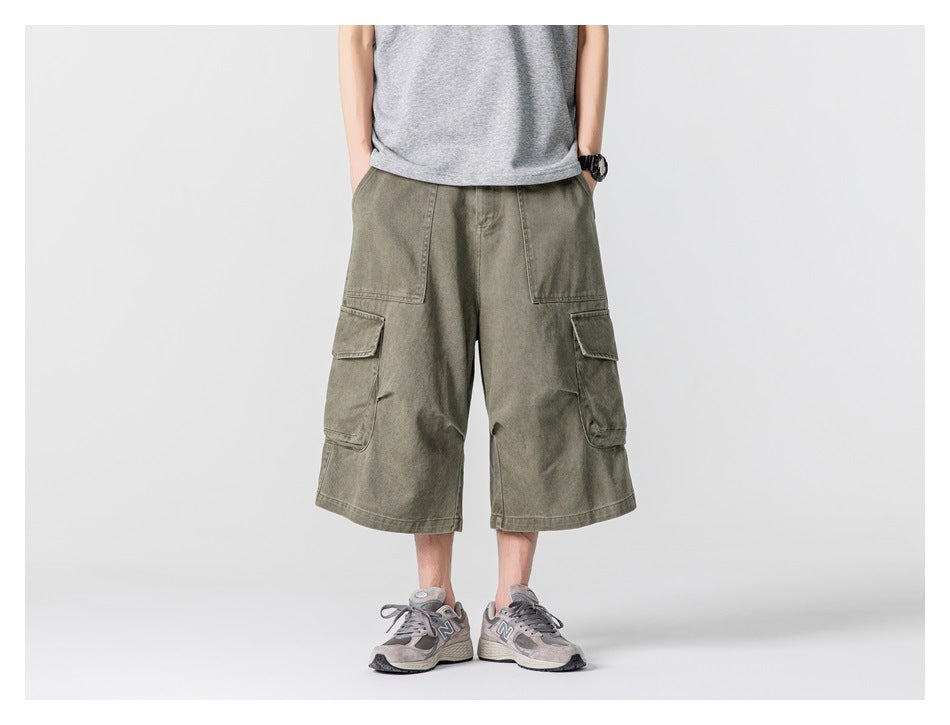Person wearing green wide-leg cargo shorts with a gray T-shirt and gray sneakers, front view