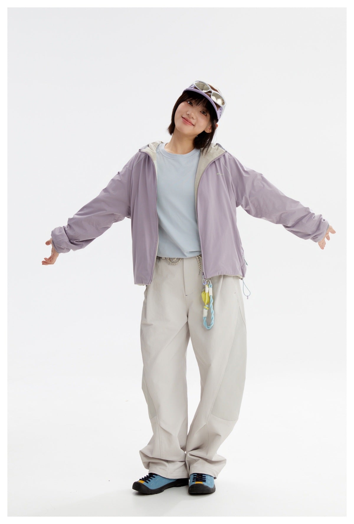 Model wearing a lavender hooded zip jacket over a pale blue shirt and loose off-white trousers.