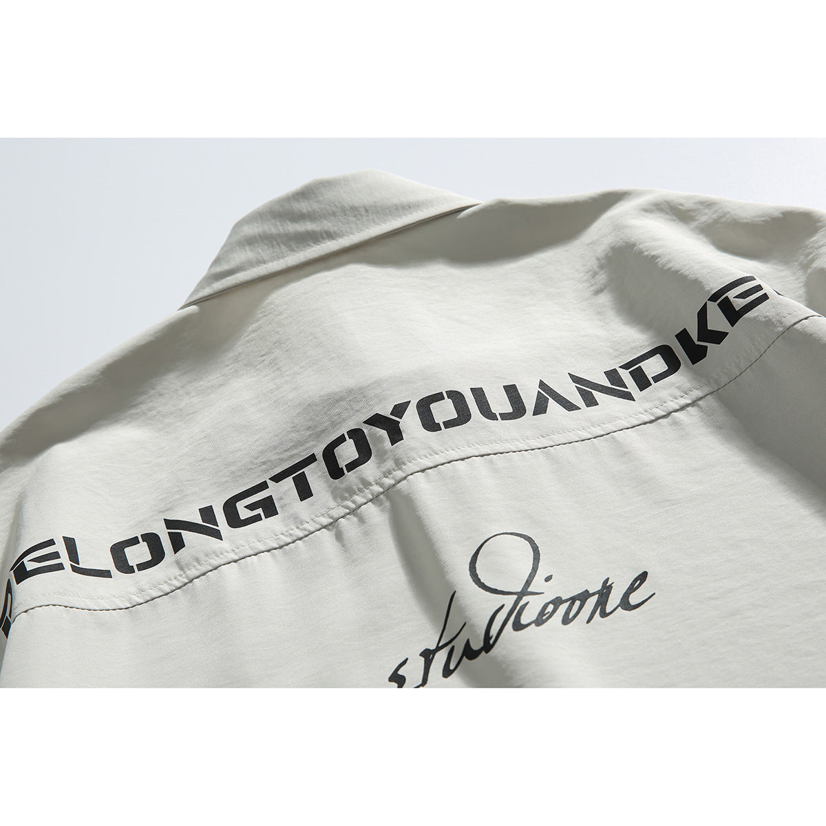 Close-up of black lettering across the back yoke of a light gray shirt.