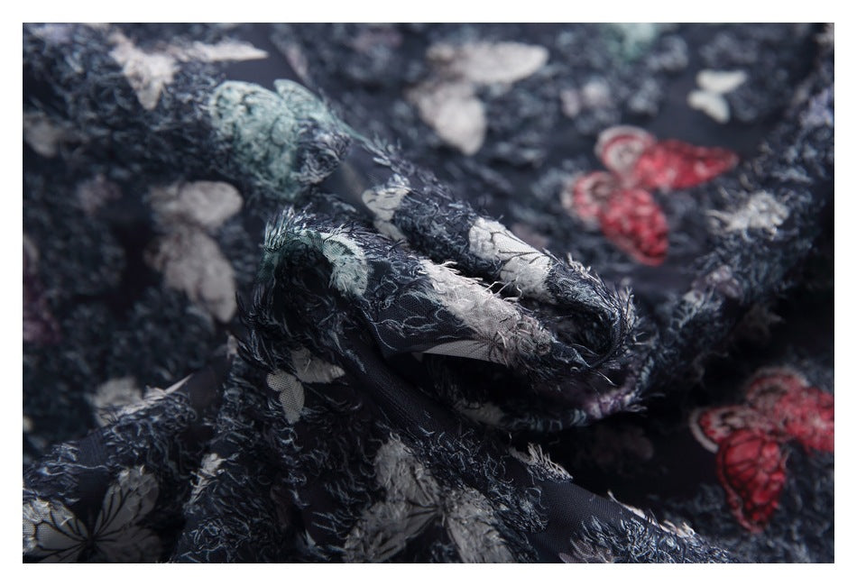 Macro view of dark navy fabric with colorful butterfly prints and a fuzzy, textured surface.