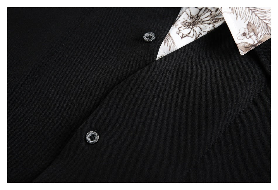 Close-up of a black garment's front placket with two dark decorative buttons and a floral collar edge.