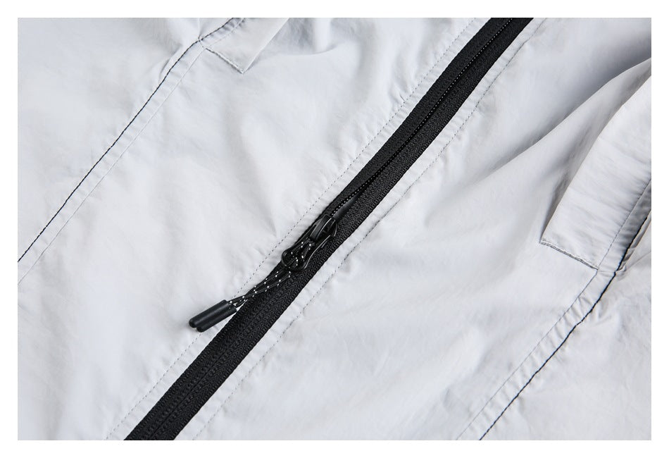 Close-up of a black two-way zipper with cord pulls on a light gray jacket.