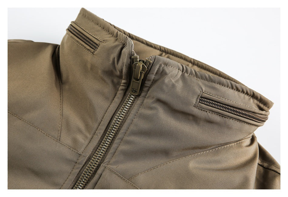 Close-up of tan trousers showing the front zipper, waistband, and two small zip pockets.