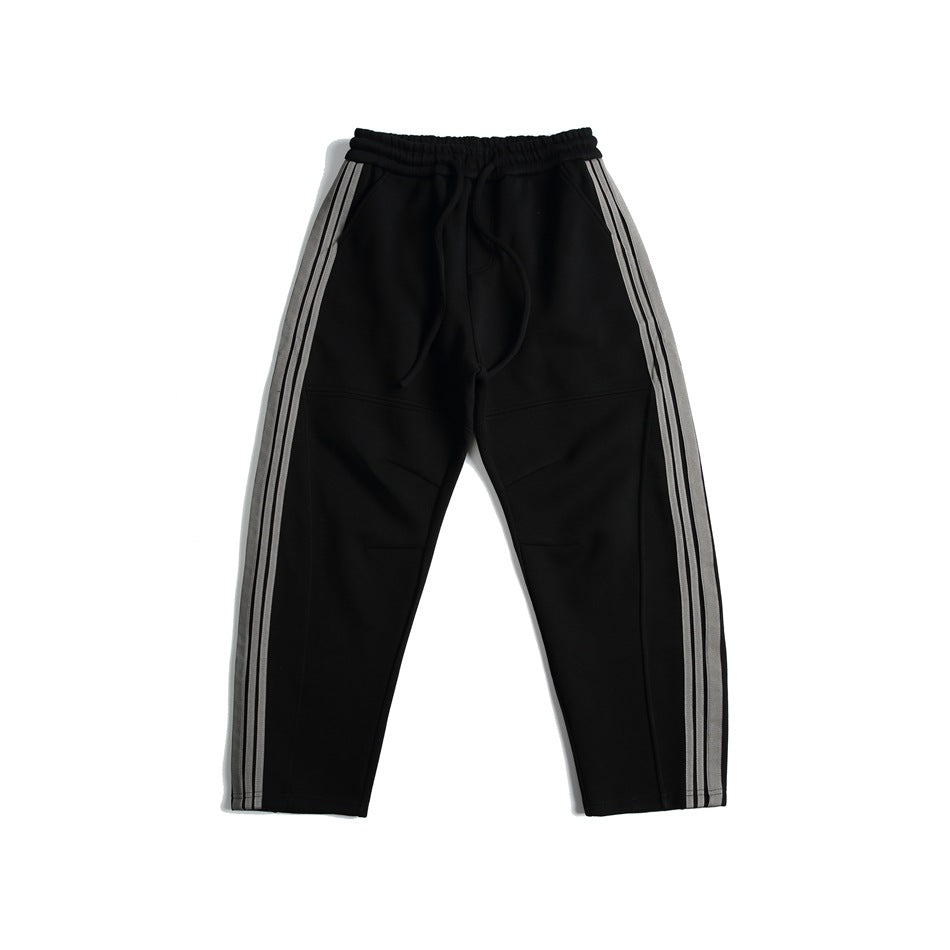 Black sweatpants with gray triple side stripes and drawstring elastic waist, flat lay front view
