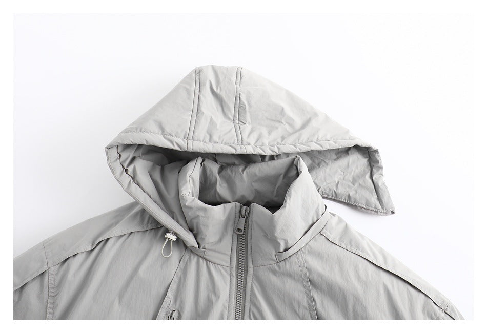 Close-up of a light gray jacket front with a large hood draped over its high collar and center zipper.