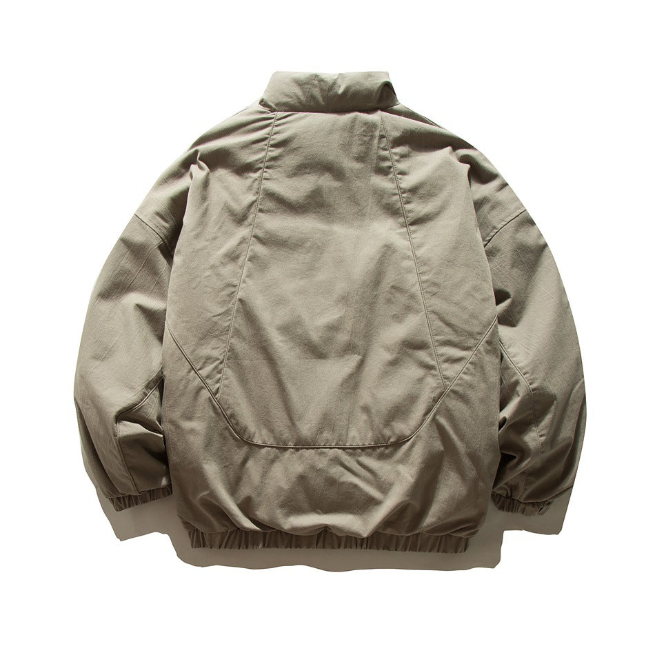 Back view of a beige jacket with a stand collar, curved seams, and gathered elastic cuffs and hem.