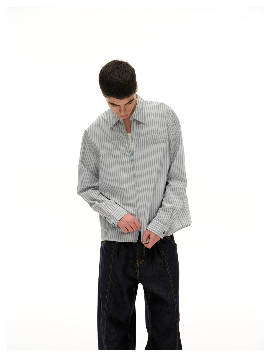 Closer view of a model wearing a gray pinstriped shirt with a chest pocket and pale blue front zipper.