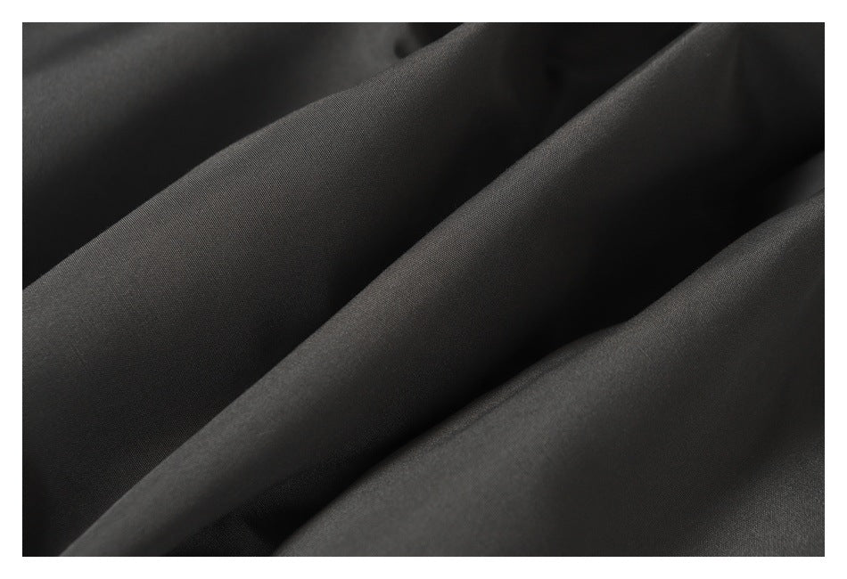 Macro view of charcoal jacket fabric arranged in soft folds.