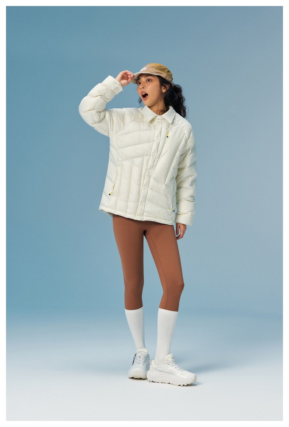 Model poses in an ivory quilted collared jacket with snap buttons and brown leggings.