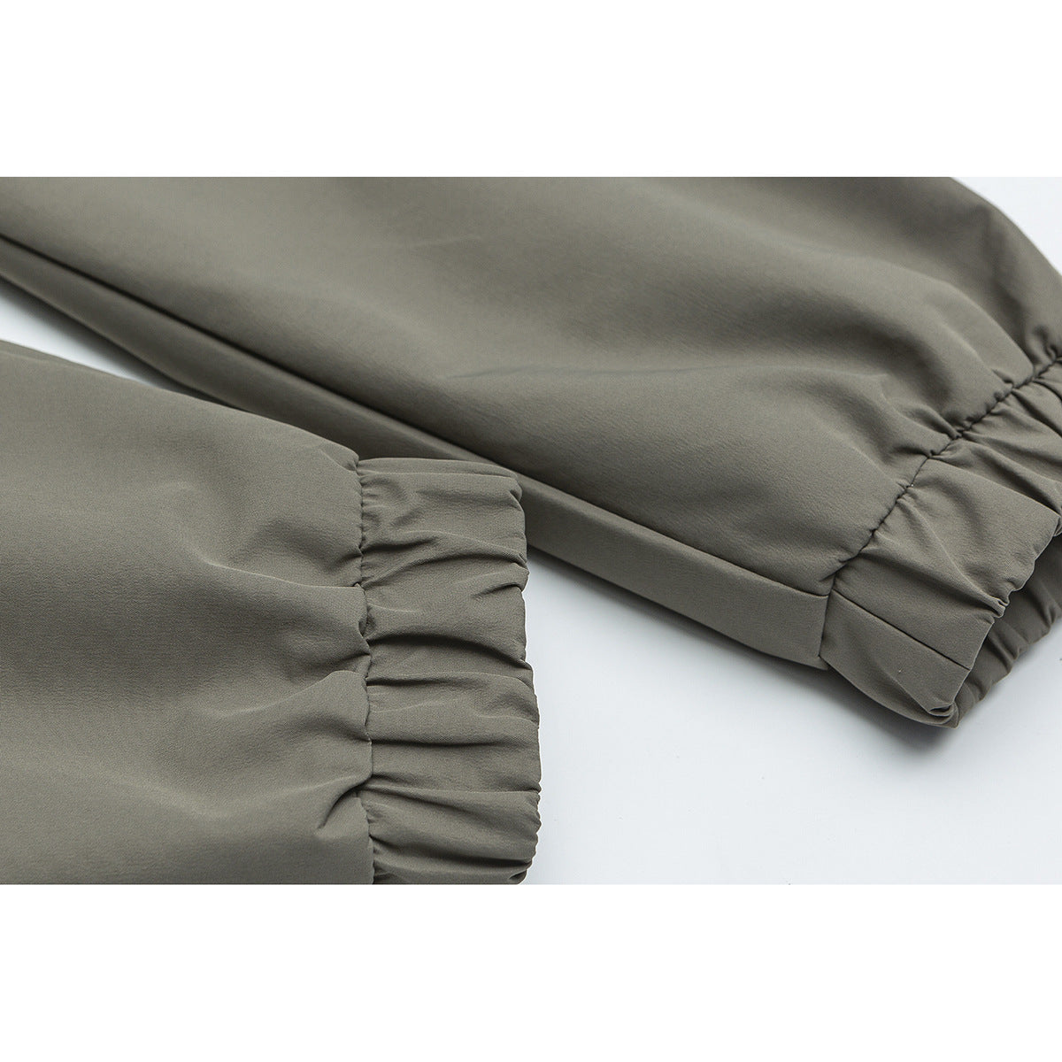 Close-up of olive-gray jacket sleeves with gathered elastic cuffs.