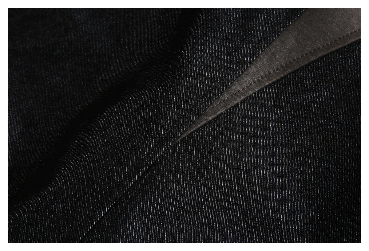 Close-up of black textured fabric with a diagonal smooth dark panel and stitched edge.