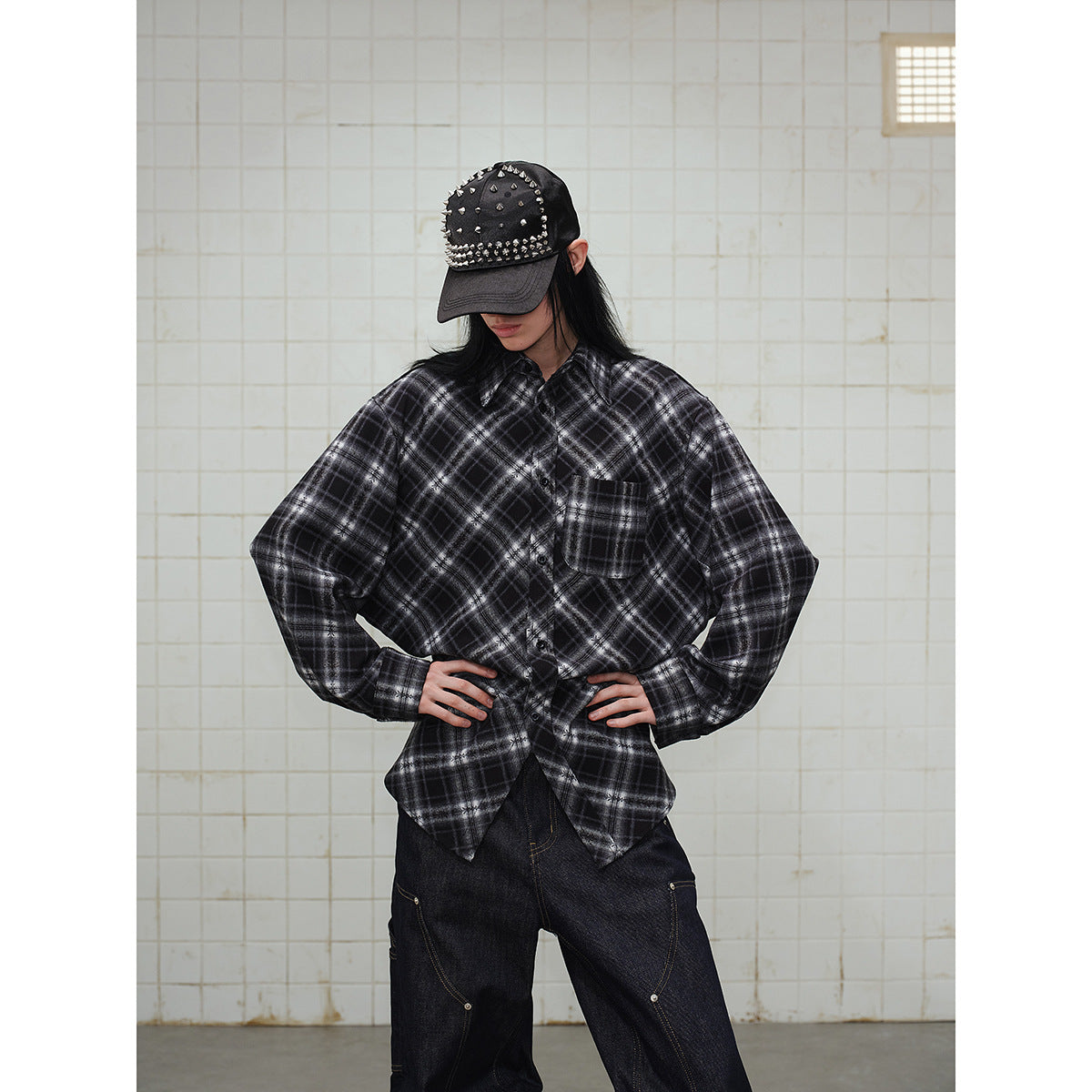 Model wearing an oversized black and gray plaid button-up shirt with a chest pocket and long sleeves.
