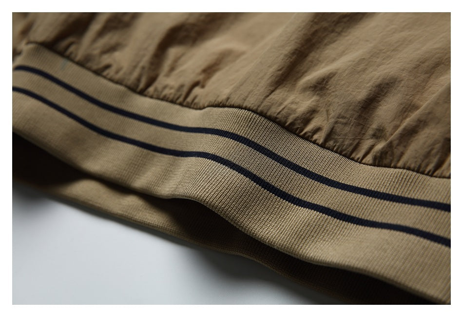 Close-up of a tan jacket hem with ribbed beige trim and two dark stripes.