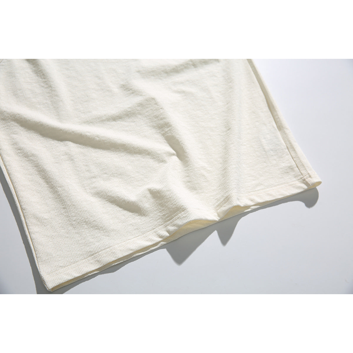Close-up of the cream tank top's straight stitched hem and fabric.