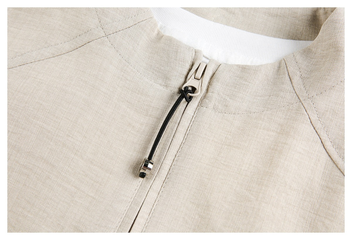 Detailed view of an ivory jacket's collar, stitching, and zipper with a black cord pull.