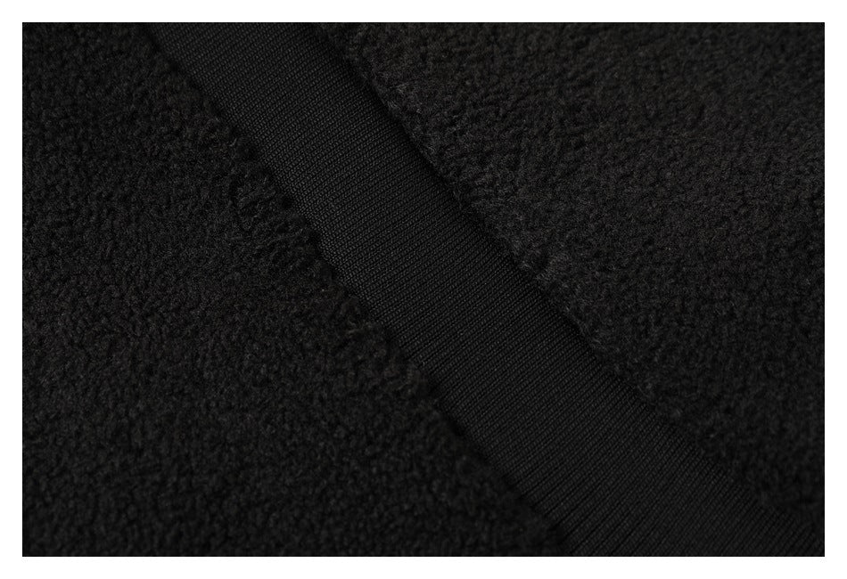Close-up of a black ribbed strip crossing the jacket’s textured fabric.
