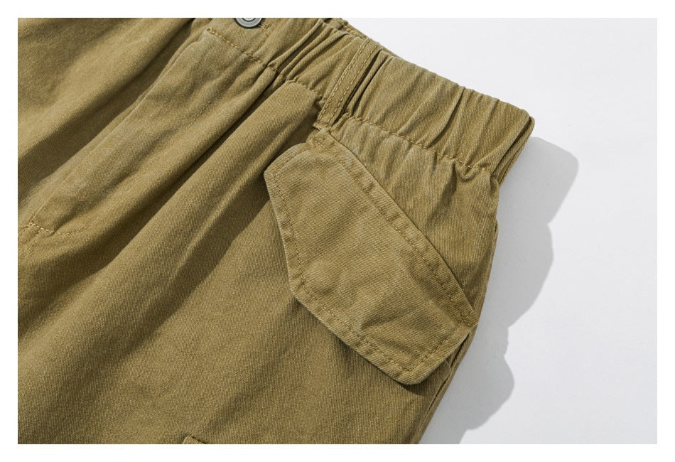 Close-up of olive-khaki cargo shorts showing an elastic waist and a flap pocket.