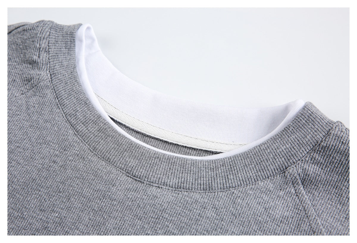 Close-up of a gray shirt's ribbed crew neckline, showing white inner trim and stitching.