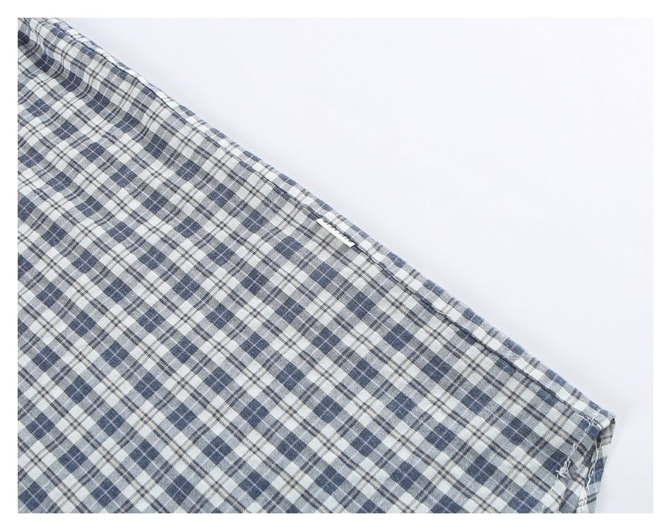 Close-up of a sleeve seam on a blue, gray, and white plaid shirt.