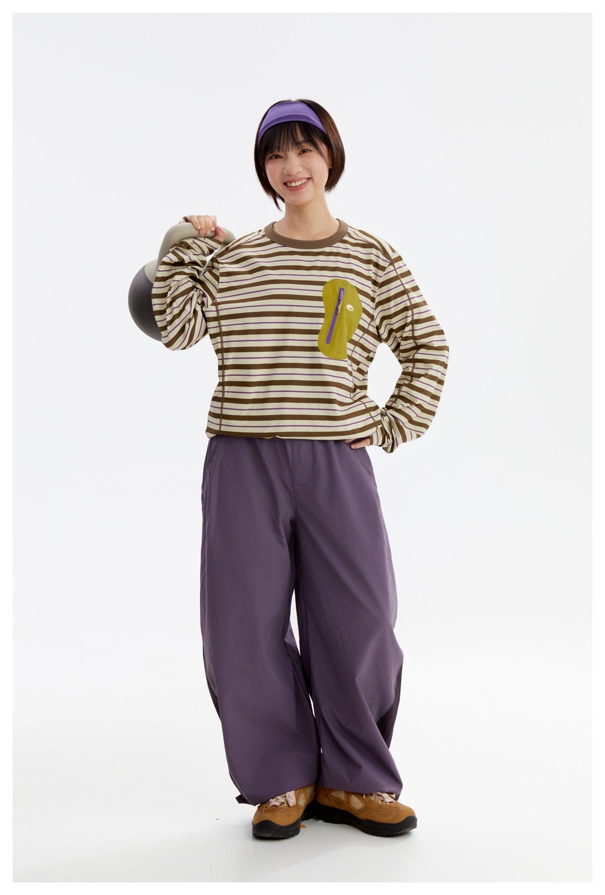 Model wearing a cream-and-brown striped long-sleeve top with a yellow chest pocket and wide purple pants.