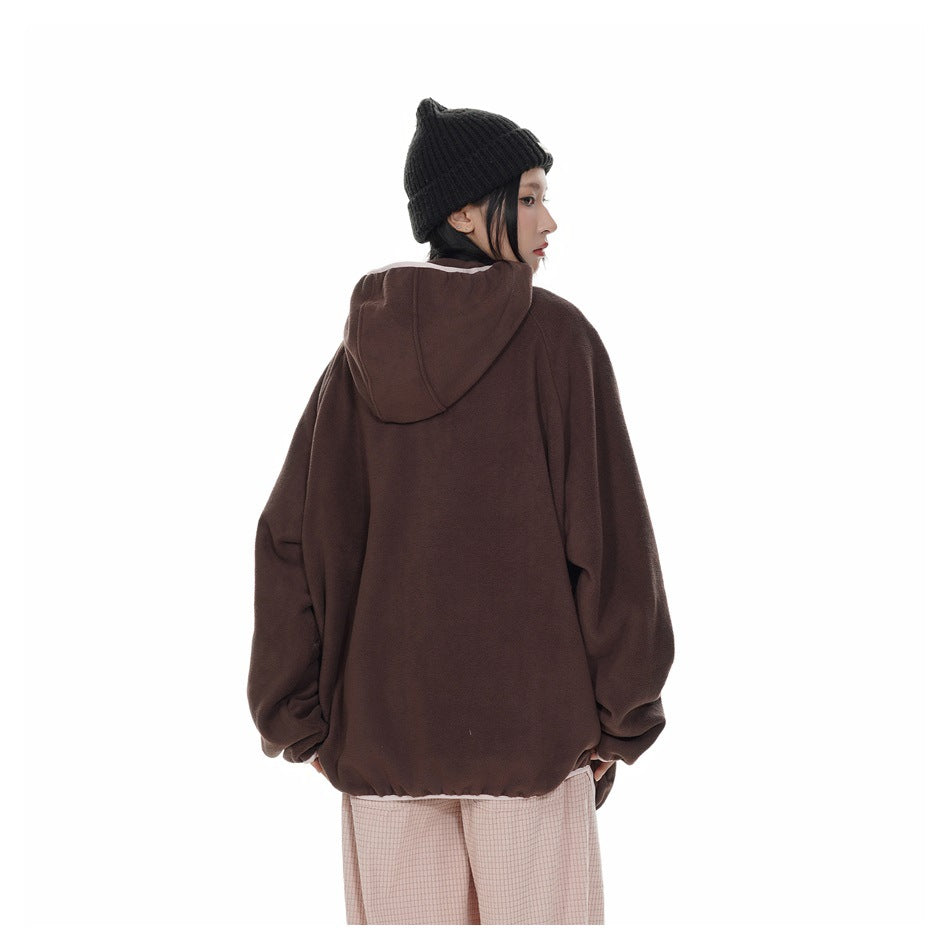 Rear view of a model wearing an oversized dark brown hooded jacket and pale pink trousers.