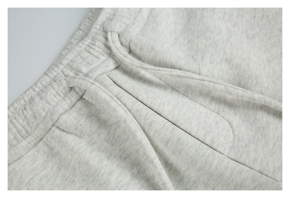 Close-up of the drawstring waistband and slanted pocket on light gray marl sweatpants.
