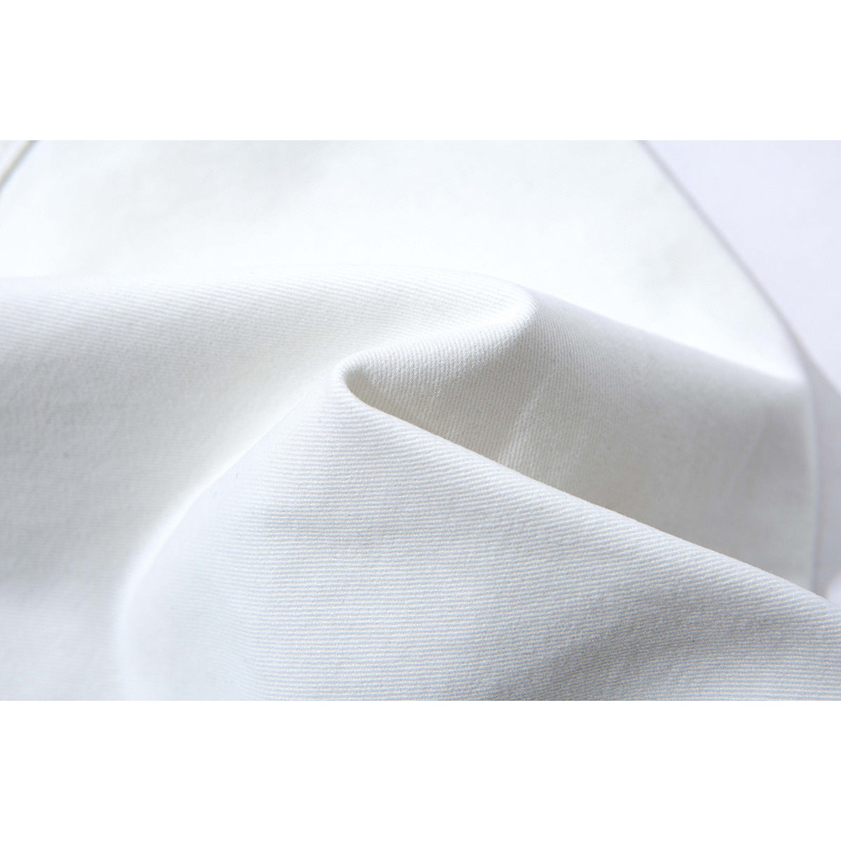 Macro view of white pant fabric folded to show its surface and weave.