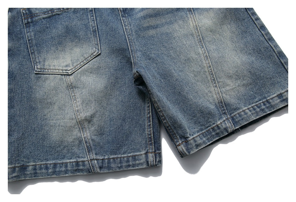 Close-up of blue denim shorts showing a rear patch pocket, faded wash, seams, and hems.