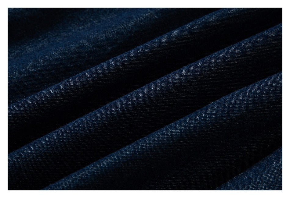 Extreme close-up of dark indigo fabric arranged in folds, showing its woven texture.