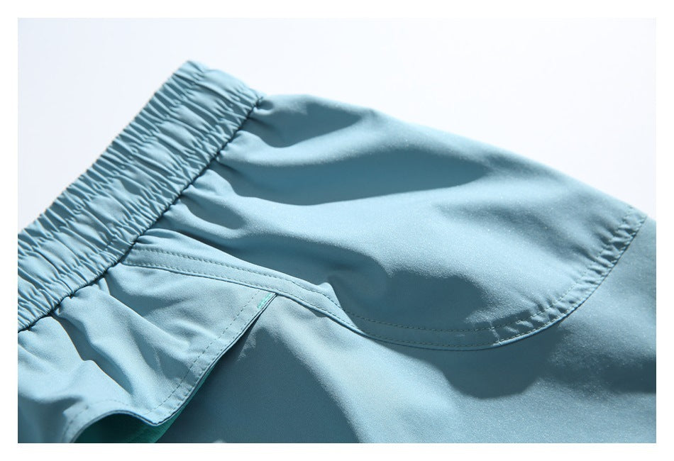 Close-up of light blue shorts showing the elastic waistband, curved stitched pocket, and ruffle trim.