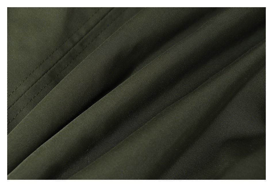 Close-up of olive garment fabric folds and parallel stitching.