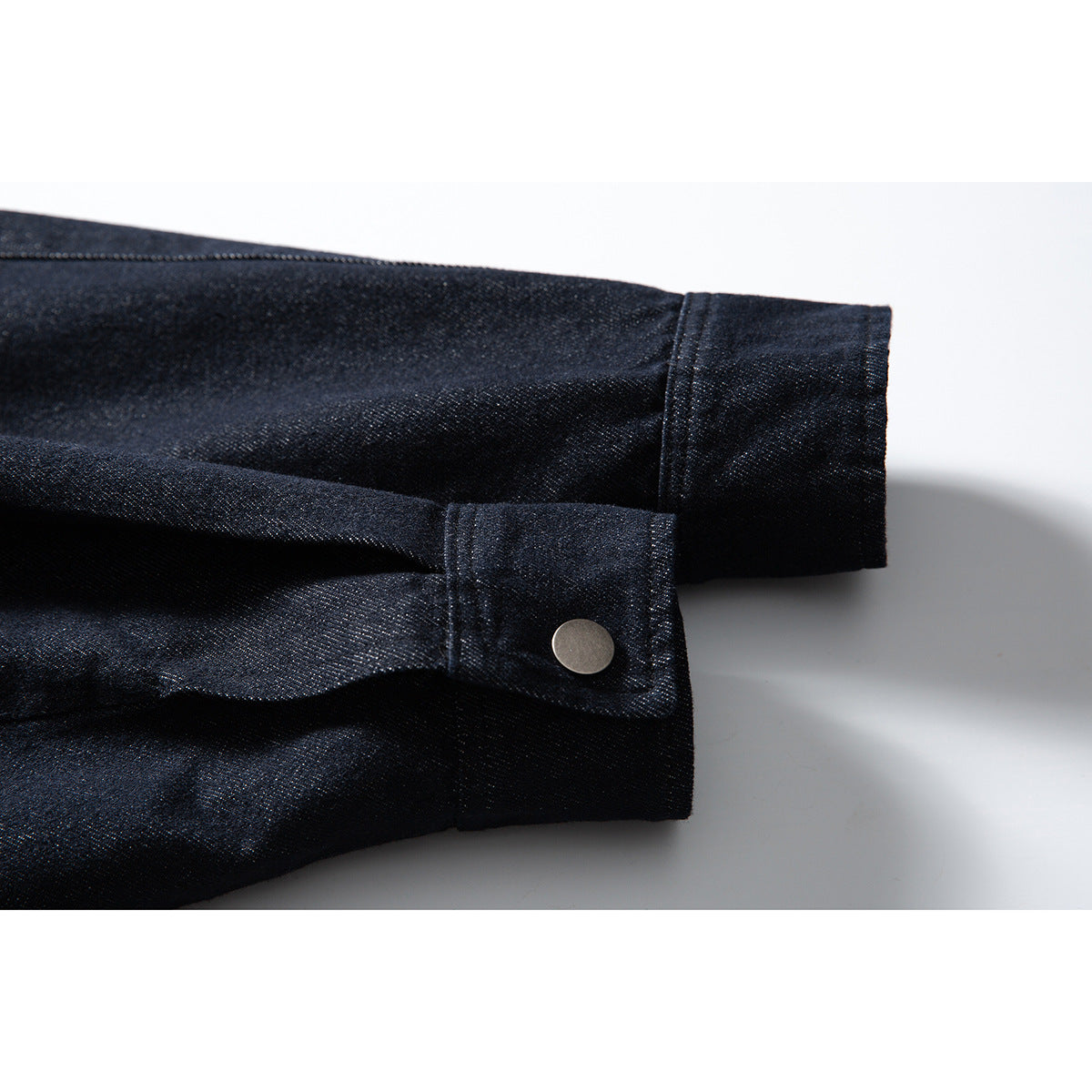 Close-up of a dark indigo jacket sleeve and cuff with a metal snap button.