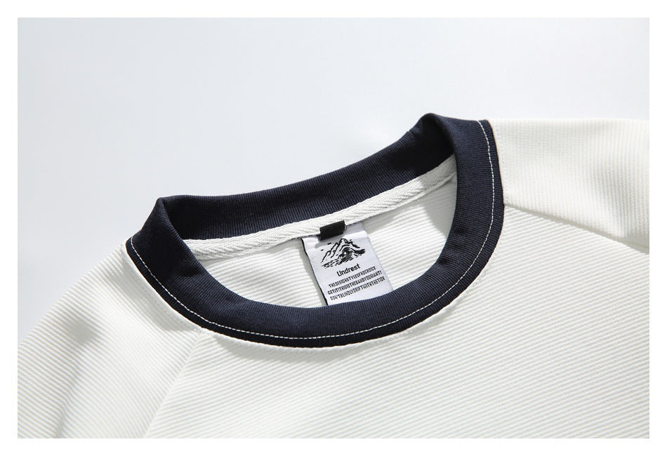 Close-up of the white ribbed shirt's black-trimmed crew neck and sewn-in label.
