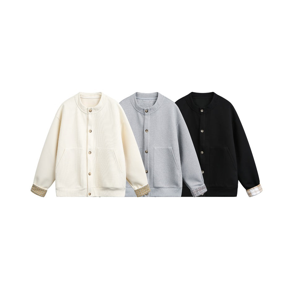 Three button-front jackets in cream, gray, and black, with stand collars, front pockets, and plaid turn-back cuffs.