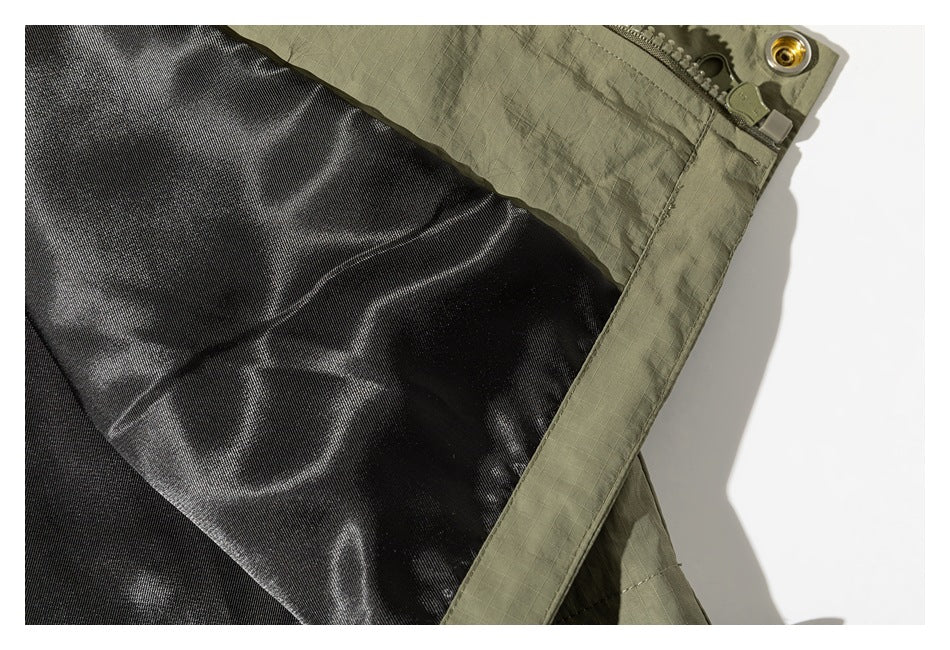 Close-up of an olive-green jacket opening with black lining, zipper, and metal snap.