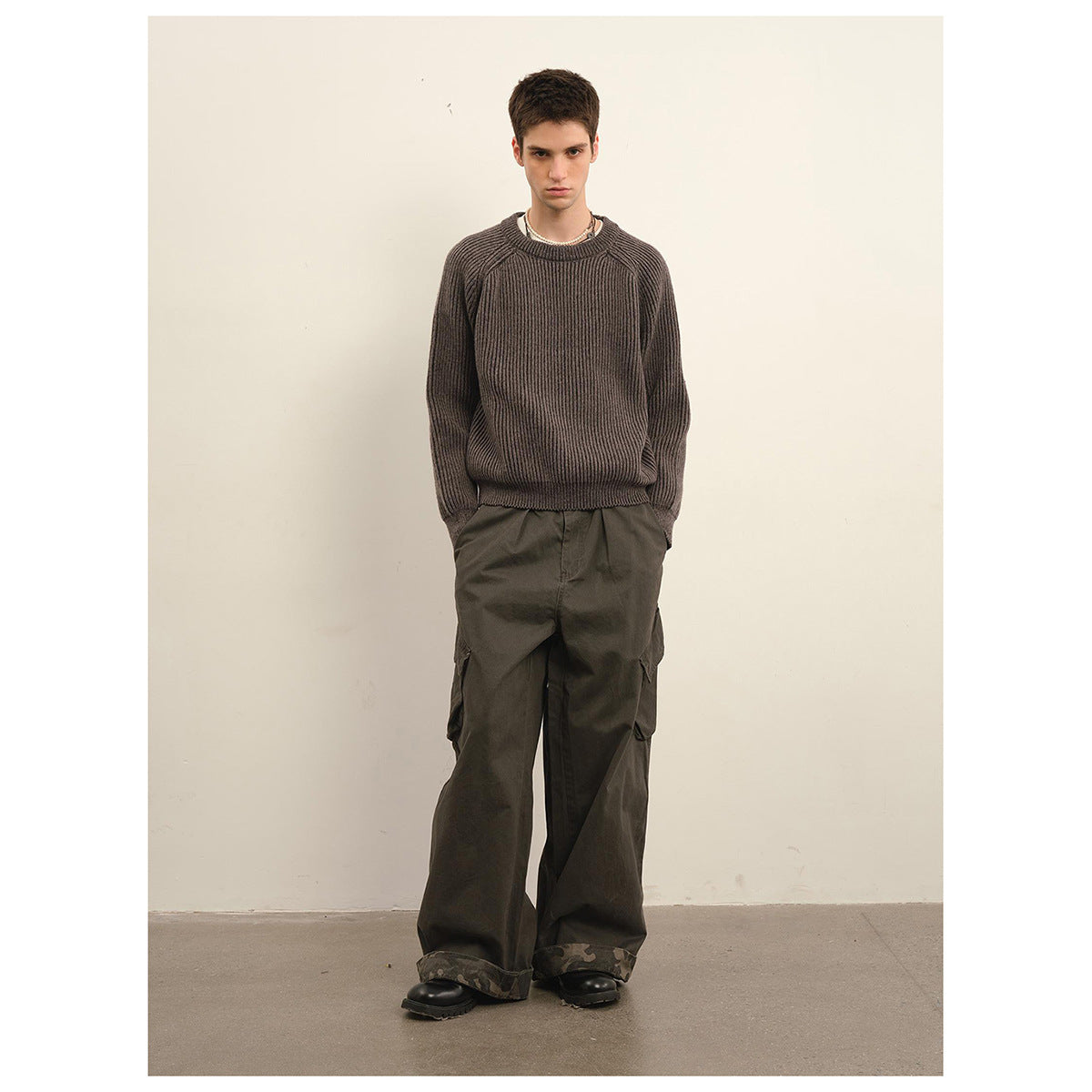 Model wearing a dark taupe ribbed crewneck sweater with raglan sleeves and charcoal cargo pants.